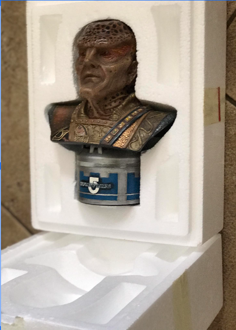Bust sculpture in a white display case with a visible brand logo.
