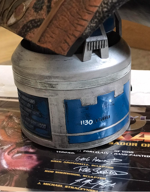 Decorative item resembling a cylindrical container with blue accents on a surface with signatures.