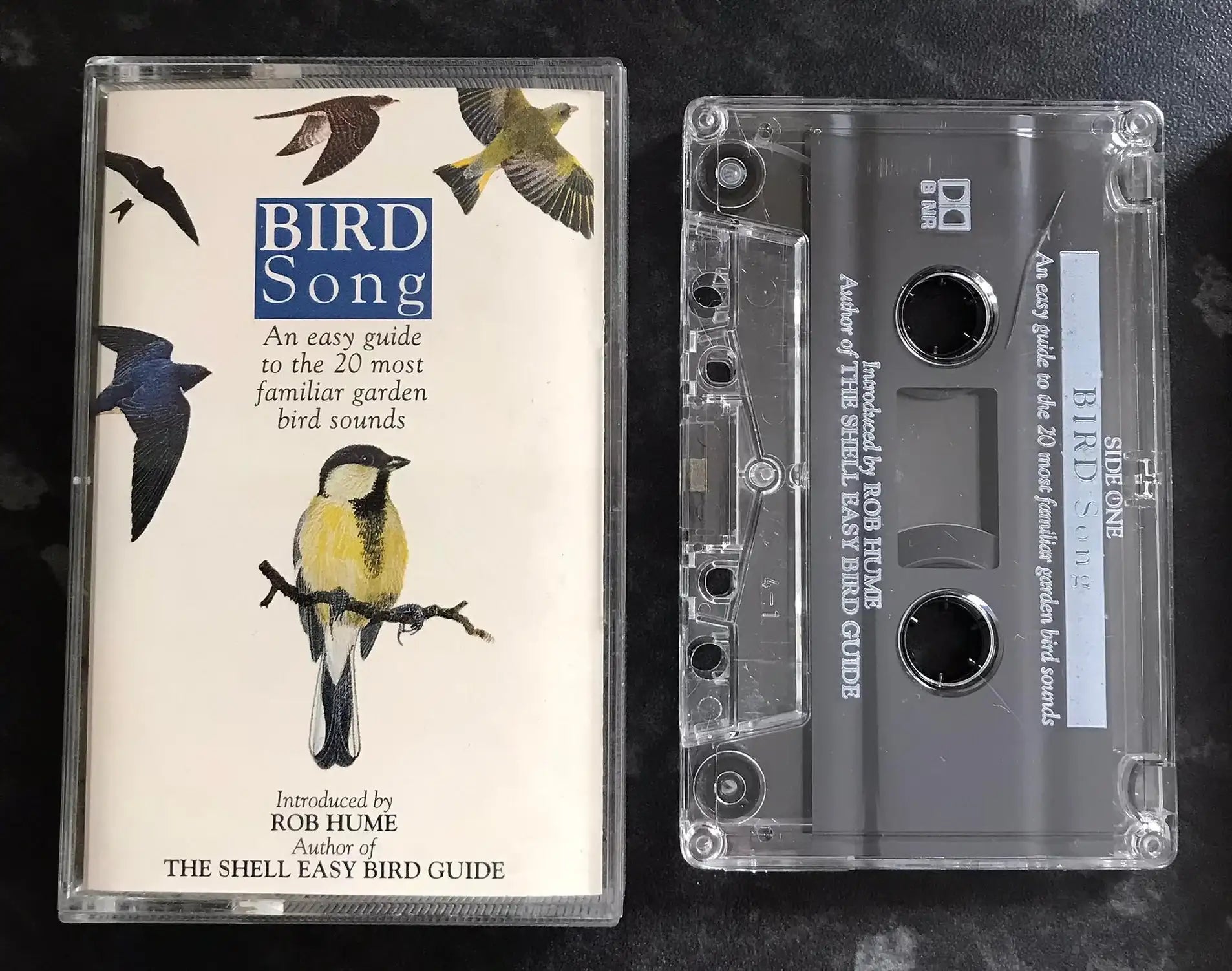 Cassette tape and its cover featuring bird illustrations on a dark background